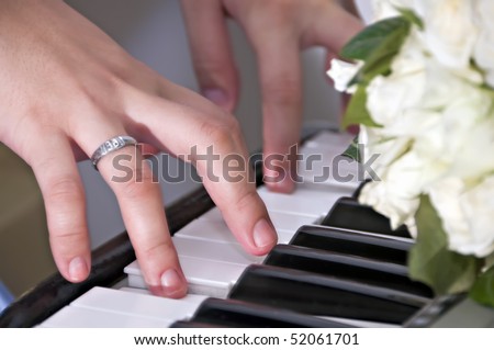 Woman\'s hands playing piano with a bunch of roses on top of piano