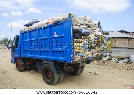 Garbage truck overflowing with trash in old sacks
