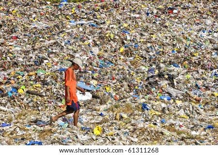 CAVITE, PHILIPPINESS. - FEBRUARY 12: An unidentified man crosses a sea of garbage on foot on February 12, 2010 in Cavite, Philippines.  Garbage disposal is a big problem in the country.