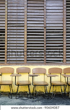 School chair-desks outside classroom with wooden jalousie windows
