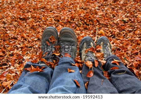 two pair of legs and hiking shoes, with autumn leafs