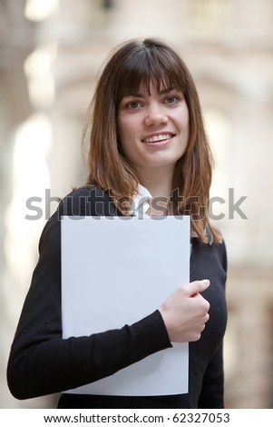 Master student outdoors holding a folder and smiling