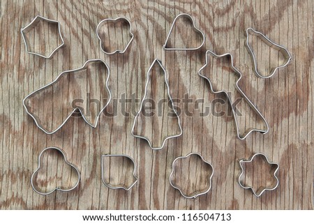 Metal molds for Christmas cookies on a wooden texture.