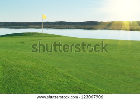 Green glade golf course, with a yellow flag.