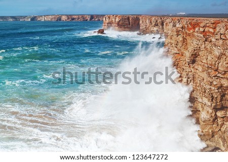 Huge waves crash against the rocks.