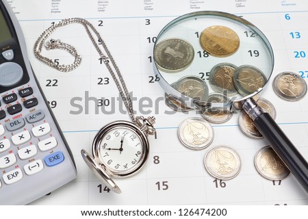Business calendar, pocket watch magnifier and money on a calendar.