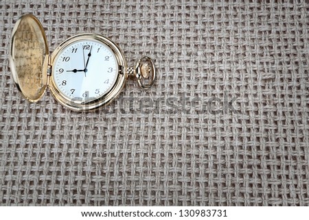 Antique pocket watch on a textured burlap. Close-up.