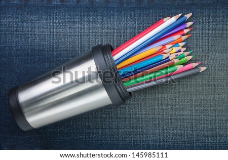 Group of colored pencils in cup with metal. On the jeans texture.