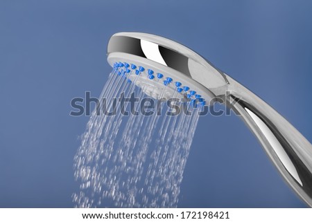 Water pours out of the shower, on a blue background.