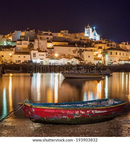 Old sea town of Ferragudo in lights at night. Boats in the foreground.