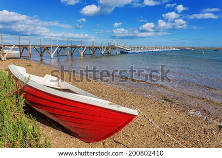 Red fishing boat on the shore. The sea.