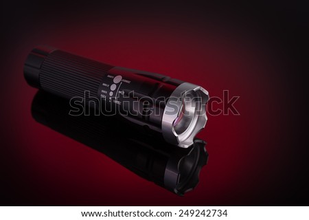 Flashlight with LED light. On a red background.