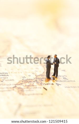 miniature businessman figurines on world map background