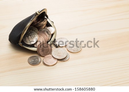 black purse with coins on wooden background