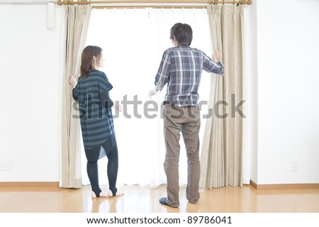 A young couple opened the curtains, look out of window