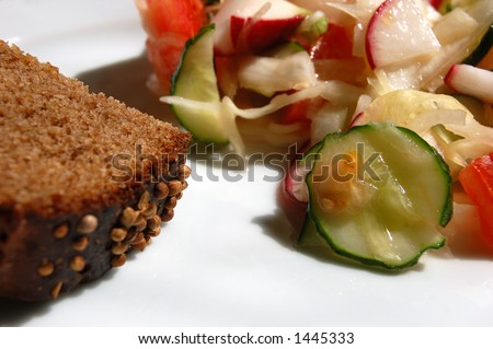 Close-up picture of vegetable salad with piece of dark bread