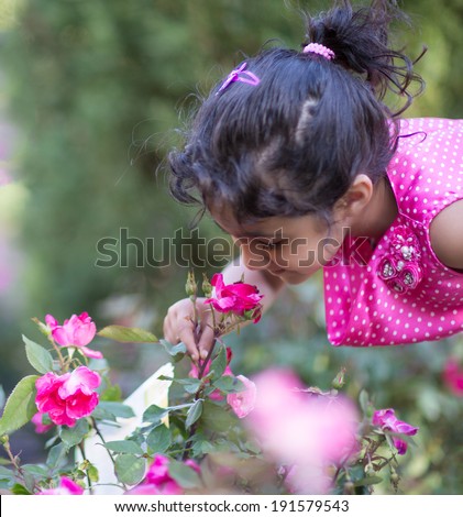 Little Girl Attempting to Smell a Rose in the Garden