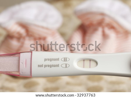 Positive Pregnancy Test and Baby Booties on a Dotted Background