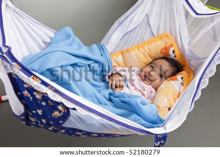 Portrait of a Smiling Baby Girl in a Traditional, Hammock-style Cradle