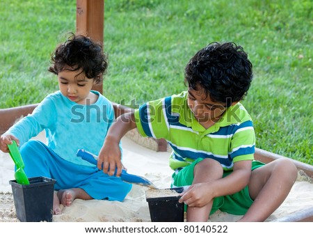 Siblings Playing in a Sand Box inside a Playset on a Summer Day