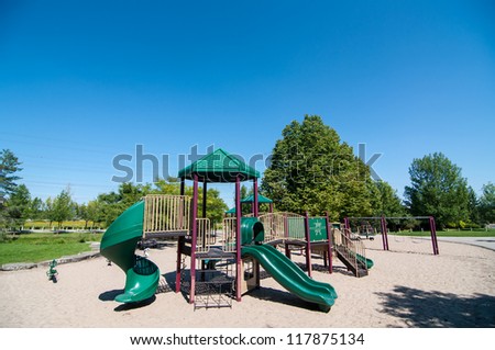 Playground equipment in a sandy play area in a public park.