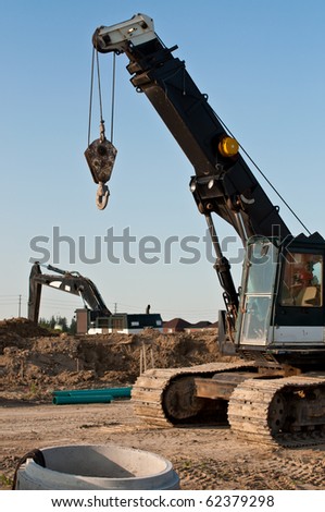A mobile crane and a hydraulic excavator at a construction site.