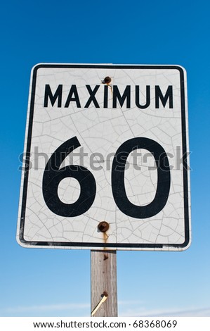 A weathered looking speed sign with a blue sky in the background.