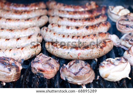 Sausages and bacon wrapped chicken cook on an outdoor grill.