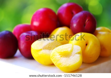 Ripe plums on wooden table and sliced plum