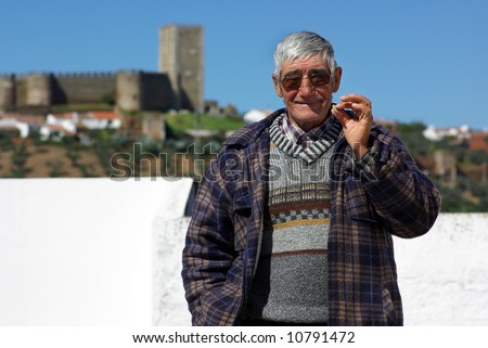 Old and happy man smokes a cigarette.