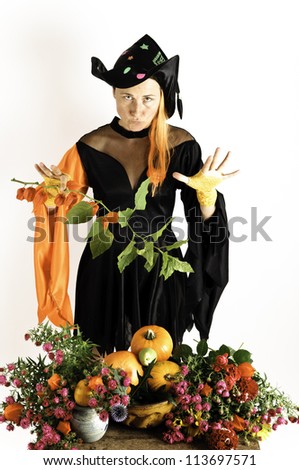 witch who charms over a table full of flowers and pumpkins
