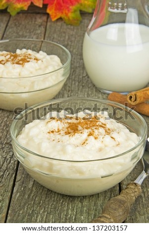 A bowl of milk rice with cinnamon on a wooden background
