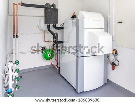 A domestic household boiler room with a new modern heating oil warm water system and pipes