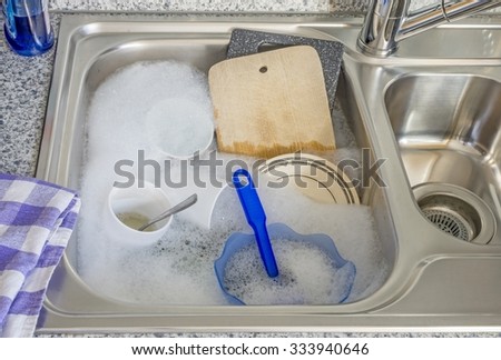 Dirty dishes in soapy water in a kitchen sink