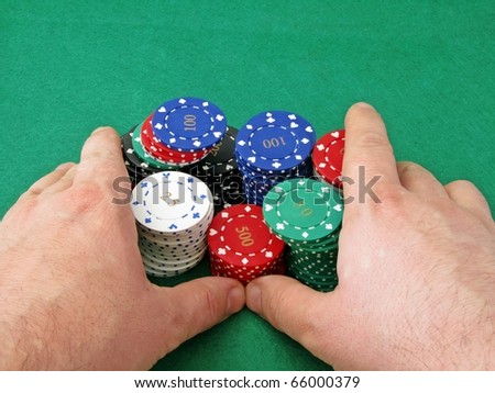 A poker players hands pushing in all his chips on a green felt background