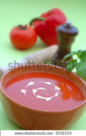 Fresh healhty tomato soup garnished with heart shaped cream drops and basil