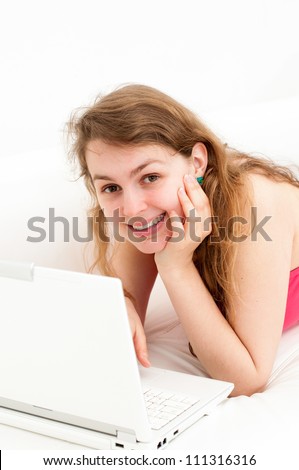 Portrait of happy young woman sitting on couch with a laptop