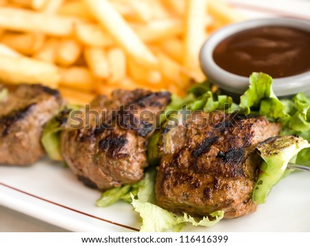 Chicken skewers with sauce and golden French fries potatoes
