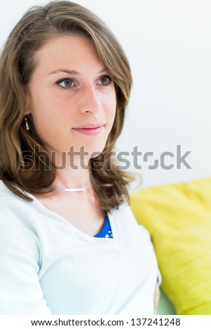 Real young woman on the couch in the living room with green pillow
