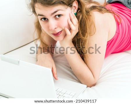 Portrait of happy young woman sitting on couch with a laptop