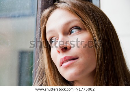 Beautiful woman standing by a window looking outside