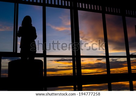 Girl standing by window at sunset with twilight sky