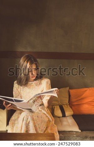 beautiful woman reading magazine in warm cozy corner, vintage style