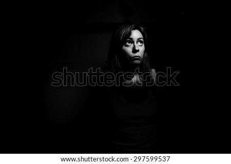 A woman trapped in the dark looking up into a shaft of light