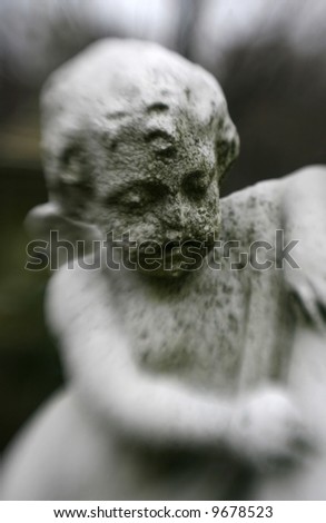 An old, deteriorating statue of an angel in a cemetery with special focus