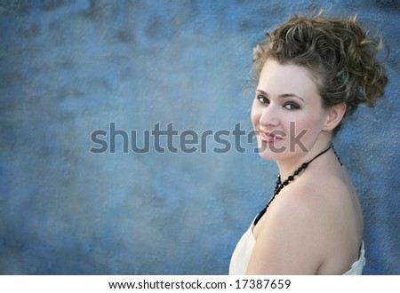 A smiling woman standing against a blue wall