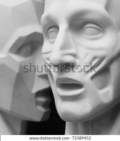 Two head sculptures with open mouth one whispers to another