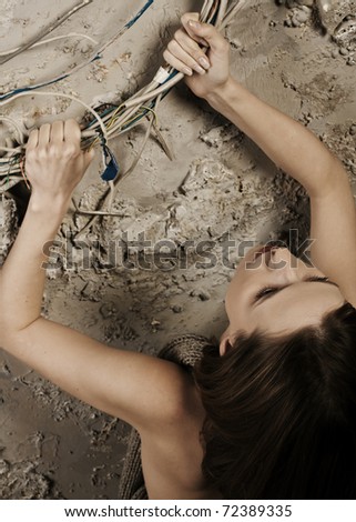Woman pulling up grabbing the wires climbing up on the concrete wall