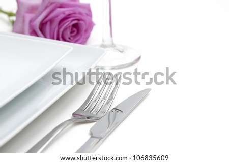 Dinner place setting. white china plates with pink rose and silver knife and fork