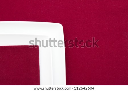 Two white square plates on red tablecloth